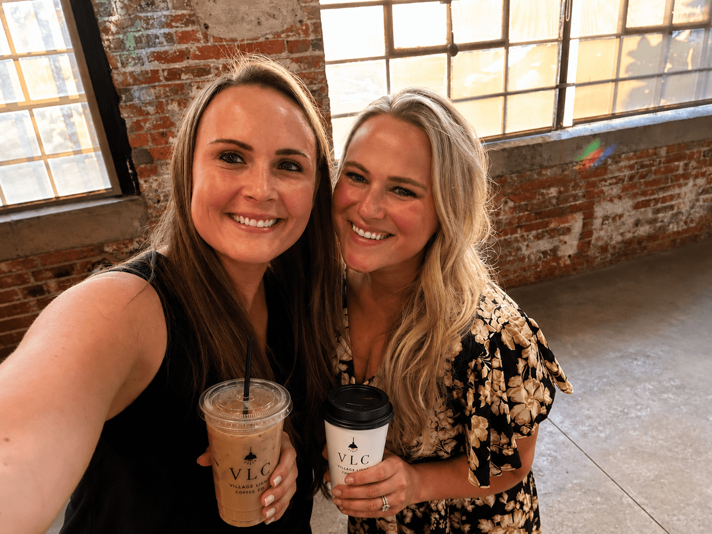 Sara and Ellen, founders of Village Light Coffee Co., holding VLC cups